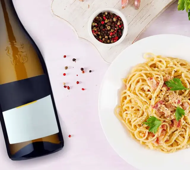 Idealne jakie wino do carbonary? Obok talerza z pysznym makaronem i butelki białego wina, pieprz i natka pietruszki.