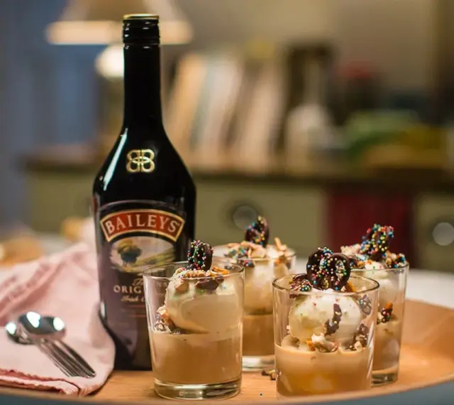 Butelka Baileys i cztery pucharki z lodami i czekoladowymi ozdobami. Idealny deser, by sprawdzić, baileys co to za smak!