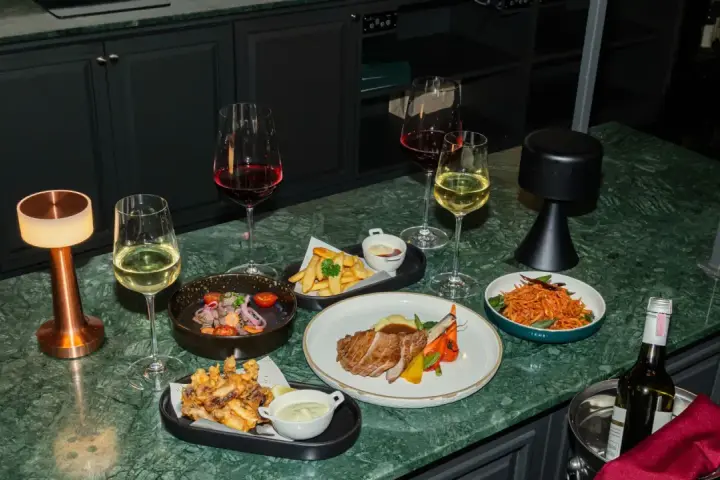 Elegancka kolacja z daniami i winem. Czy to chardonnay, jakie to wino? Obok kieliszki z białym i czerwonym winem, mięso, frytki i sałatka.