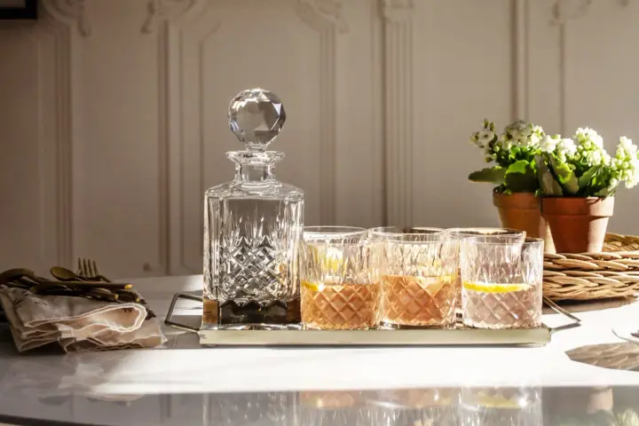 Elegancka karafka i szklanki z drinkami, idealne do serwowania bourbonu. Z czym pić bourbon? Z lodem i cytryną, jak na zdjęciu.