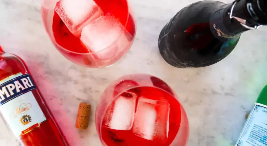 Dwa drinki z Campari, lodem i butelką prosecco. Idealne na letnie popołudnie. Campari z czym pić? Z bąbelkami!