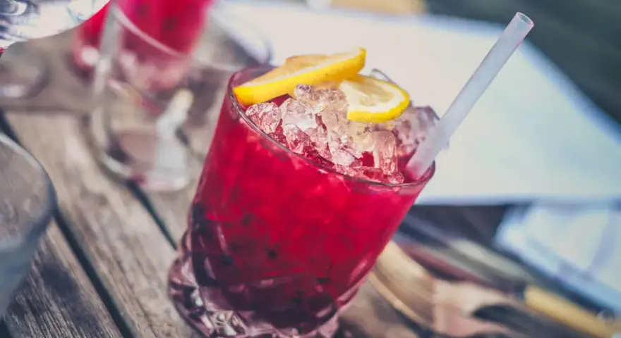 Czerwony drink z lodem i cytryną, z pewnością z dodatkiem grenadyny. Co to jest grenadyna? To syrop z granatów, idealny do koktajli.