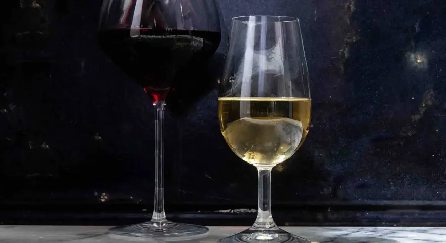 Dwa kieliszki z winem: czerwonym i białym. Białe wino, w tym wino extra dry, lśni w świetle.