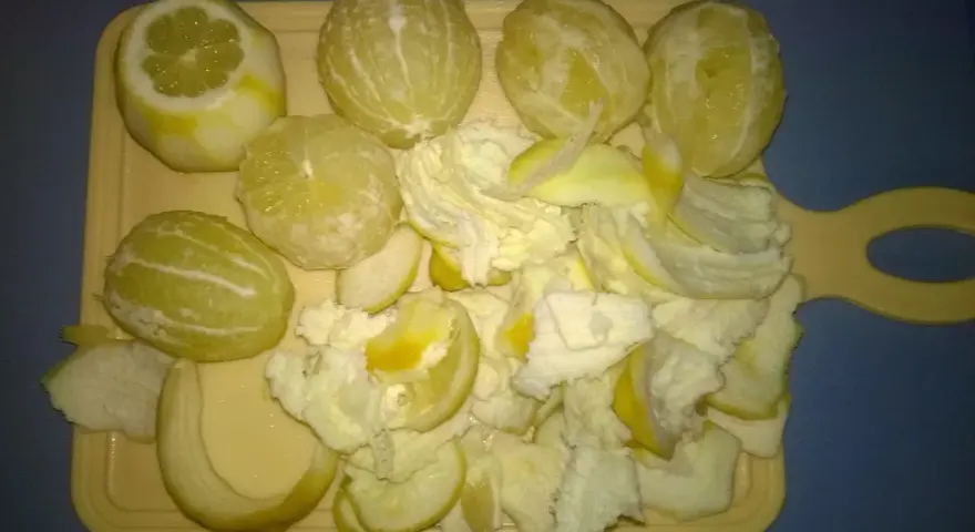Przygotowanie do zrobienia cytrynówki: obrane cytryny i skórki na desce.
