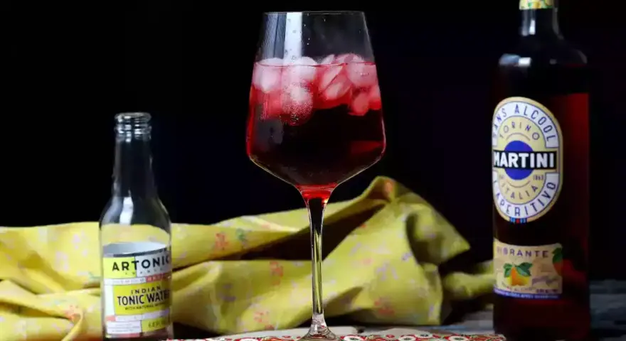 Orzeźwiający martini tonic drink z lodem, obok butelka toniku i Martini Vibrante.