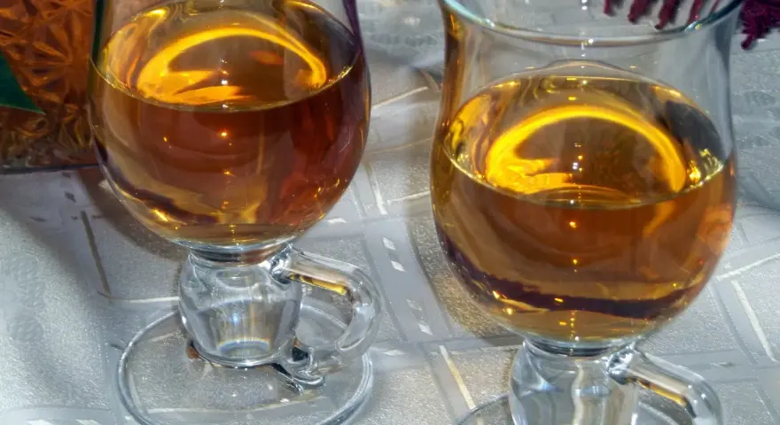 Dwa kieliszki z bursztynowym winem z ryżu i rodzynek, gotowe do degustacji.