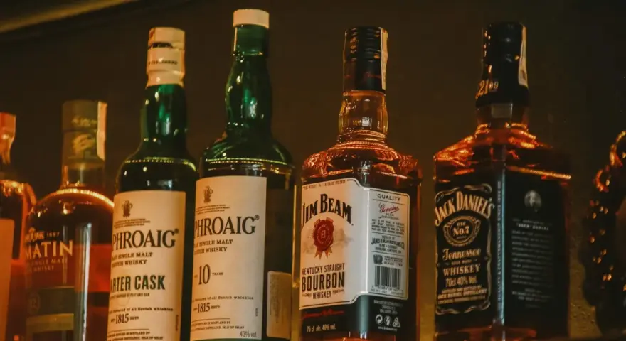 Rzędy butelek whisky: Laphroaig (43% vol.), Jim Beam (40% vol.) i Jack Daniel's (40% vol.).