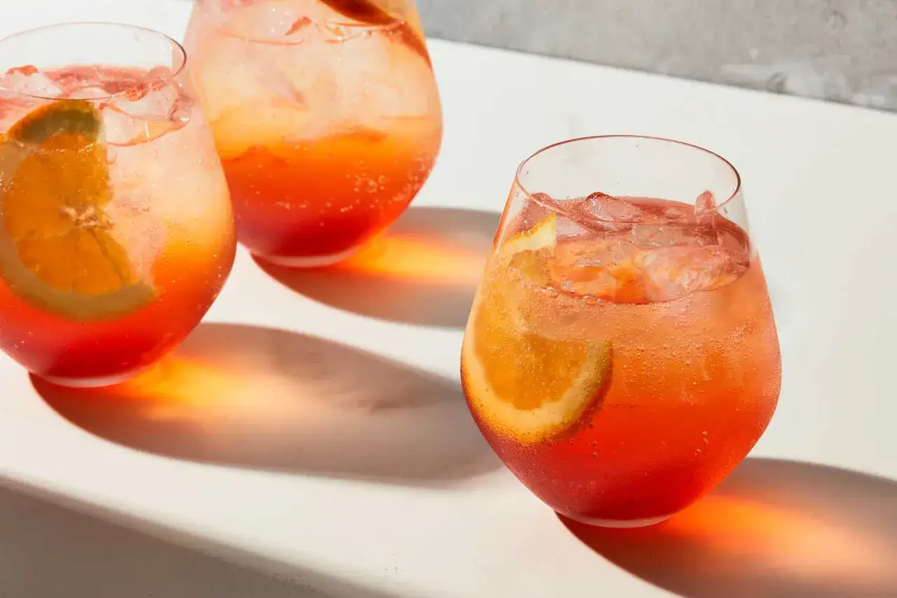Orzeźwiający Aperol Spritz z plastrem pomarańczy i lodem. Idealny aperitif, który możesz łatwo przygotować według prostego aperol przepis.