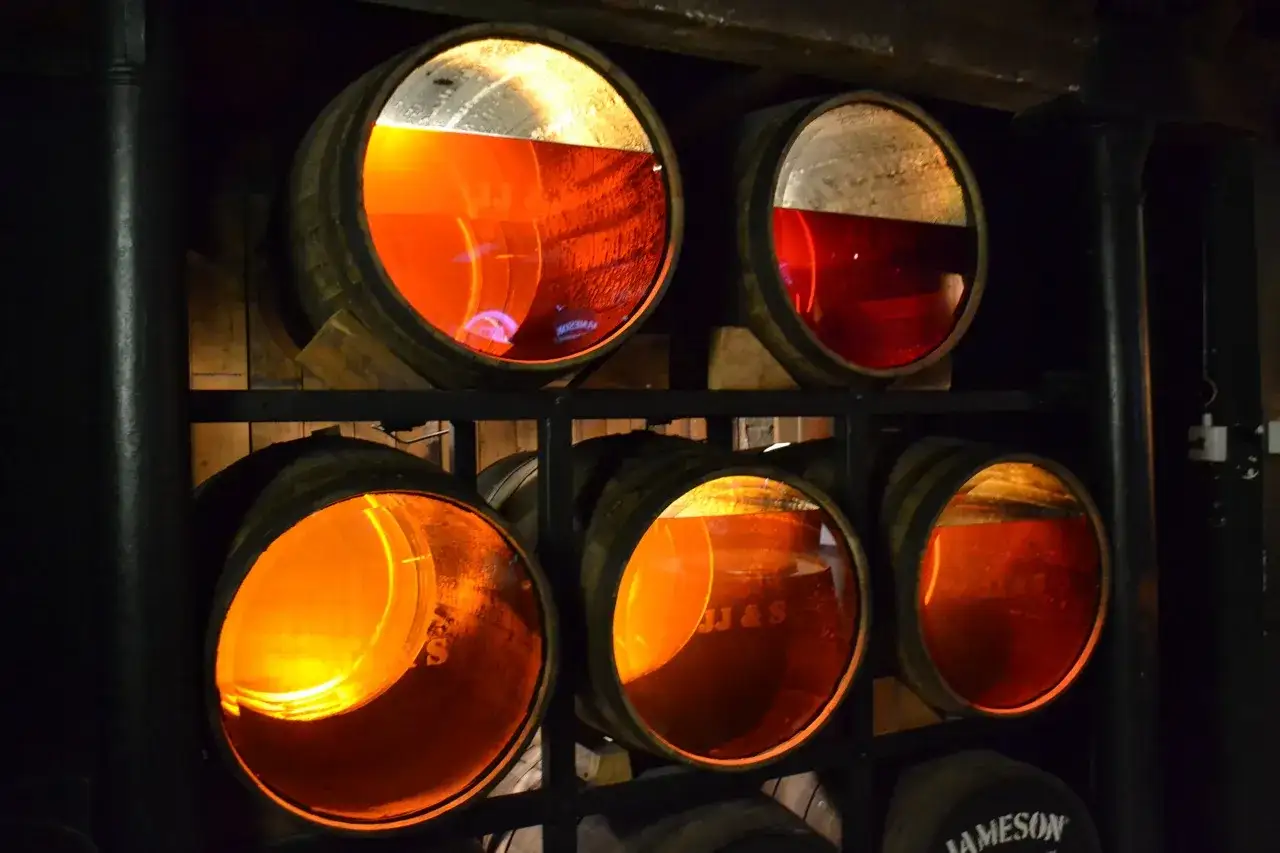 Beczki z whisky, gdzie część płynu ubyła jako whisky angel share, lśnią w ciemności.
