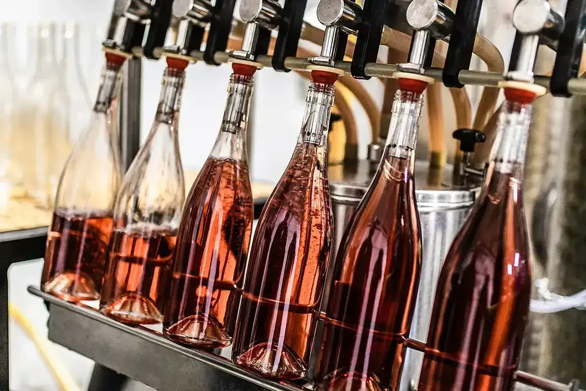 Butelki r&oacute;żowego wina napełniane są automatycznie. Kluczowa jest odpowiednia temperatura, by wino miało idealny smak.