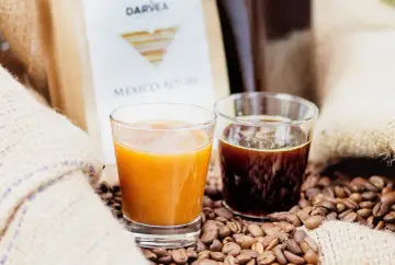Pyszny likier kawowy przepis. Dwa kieliszki z napojami, ziarna kawy i worek z napisem "Mexico Altura".